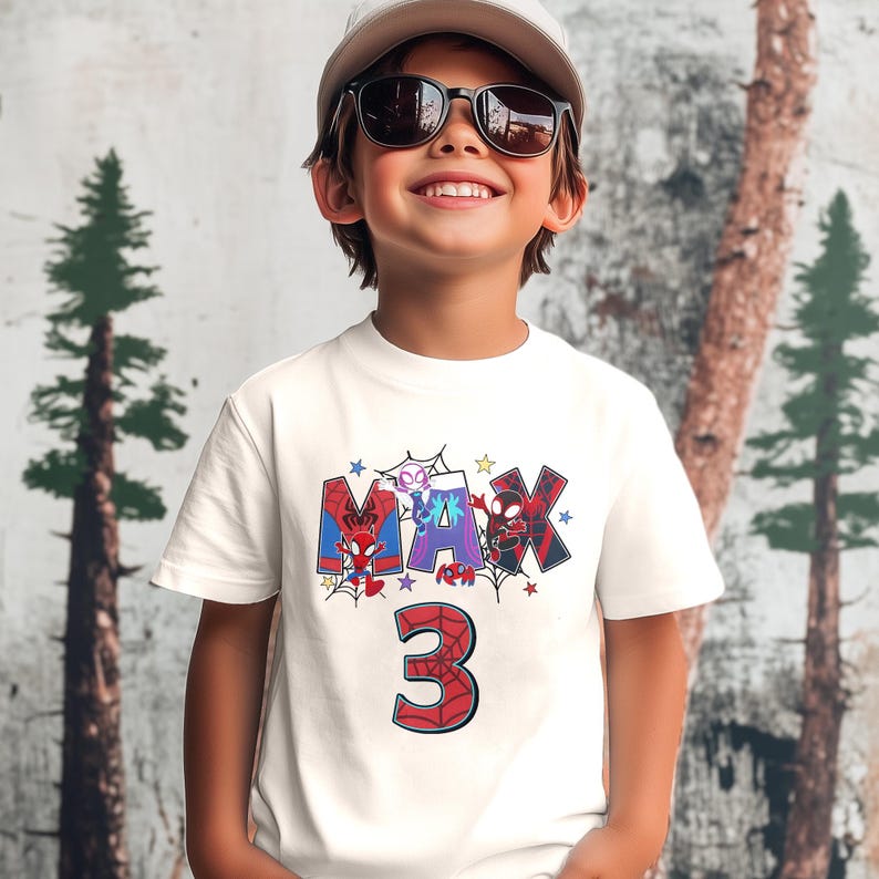 Pode incluir: Camiseta branca com um gr&aacute;fico da palavra "MAX" em vermelho, azul e preto com personagens do Homem-Aranha. O n&uacute;mero "3" est&aacute; em vermelho com detalhes do Homem-Aranha.