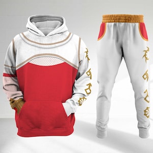 May include: A white and red hoodie and matching sweatpants set. The hoodie has a white hood and sleeves with gold trim and a red body. The sweatpants are white with gold accents and designs. The set is a matching outfit.