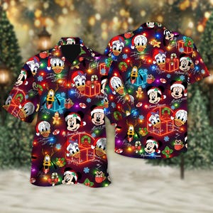 May include: Two short-sleeved button-down shirts with a festive Christmas design. The shirts feature cartoon characters like Mickey Mouse, Donald Duck, and Pluto, along with holiday elements such as gifts, wreaths, and lights. The background is a dark burgundy color.
