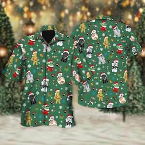 May include: Green button-up shirt with a festive pattern featuring Star Wars characters in Santa hats, snowflakes, and gift boxes. The shirt has a classic collar and short sleeves, perfect for a holiday celebration. The design includes characters like Yoda, Darth Vader, and R2-D2.