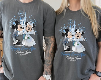 May include: Two gray t-shirts featuring a cartoon of Mickey and Minnie Mouse in wedding attire, with a castle and fireworks in the background. The text "Happily Ever After" and names are printed below the image.