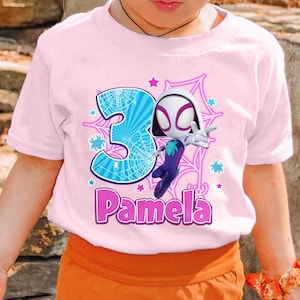 May include: Pink t-shirt with a graphic of Spider-Gwen, a blue number 3, and the name "Pamela" in pink letters.