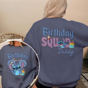 以下が含まれることがあります： 青いスウェットシャツに、誕生日帽子をかぶり、ケーキを持っているスティッチのキャラクターが描かれています。キャラクターの上に「Birthday Squad」という文字、下に「Daddy」という文字が書かれています。