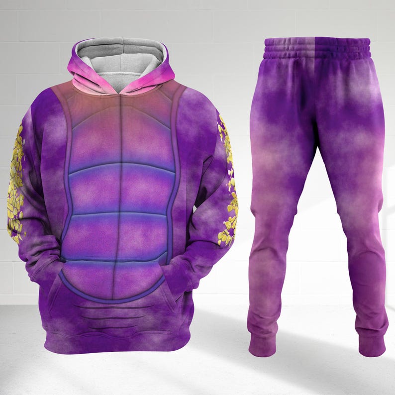 Op de afbeelding: Een paarse hoodie en bijpassende joggingbroek set. De hoodie heeft een schildpadschildontwerp, met gouden bloemaccenten op de mouwen. De joggingbroek heeft een verloop van paarse tinten. De set is gemaakt van een zacht materiaal.