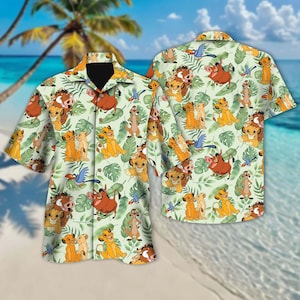 May include: A green and white button-up shirt with a repeating pattern of cartoon lions, warthogs, and birds. The shirt has a short sleeve and a collar.