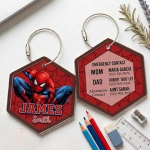 May include: Two hexagonal keychains with metal wire loops. One features a red and blue superhero graphic with the text JAMES SMITH. The other displays EMERGENCY CONTACT information for MOM MARIA GARCIA, DAD ROBERT BOB LEE, and AUNT SARAH.