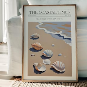 May include: A framed art print titled "The Coastal Times" featuring an illustration of seashells on a sandy beach with waves. The artwork has a neutral colour palette with beige, blue, and brown tones. The print is displayed on a white sofa.