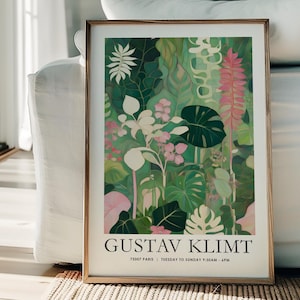 May include: A framed art print featuring a botanical illustration with a variety of green leaves, pink flowers, and white accents. The print is in a gold frame and includes the text "GUSTAV KLIMT" and other text below. The artwork is displayed indoors.