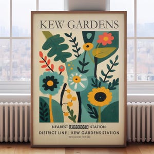 May include: A framed art print featuring a colorful floral design with the text "KEW GARDENS" at the top. The artwork includes various flowers and foliage in shades of blue, yellow, and red. The bottom text reads "NEAREST UNDERGROUND STATION DISTRICT LINE | KEW GARDENS STATION".