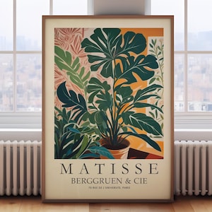 Puede incluir: Un cuadro enmarcado con una ilustraci&oacute;n de una planta en maceta con grandes hojas verdes. La obra de arte, en tonos c&aacute;lidos, incluye el texto "MATISSE BERGGRUEN & CIE 70 RUE DE L'UNIVERSITE. PARIS". La impresi&oacute;n se muestra en una habitaci&oacute;n con una ventana.