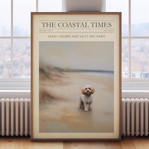 May include: A framed print titled "The Coastal Times" featuring a beach scene with a small, fluffy dog. The print has a light brown wooden frame. The text on the print reads "Sandy Shores and Salty Wet Paws."