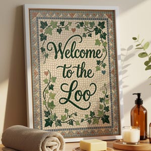 May include: A framed rectangular wall art piece featuring a mosaic-style background with green ivy vines and the text Welcome to the Loo in dark green script. The border consists of small geometric tiles in shades of gray, brown, and blue.