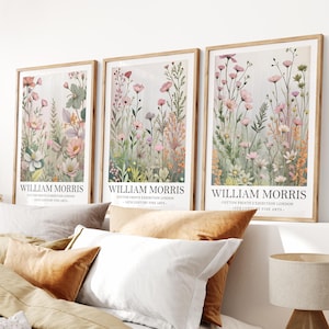 Może przedstawiać: Trzy oprawione grafiki z motywem kwiatowym z tekstem "WILLIAM MORRIS" i "COTTON PRINTS EXHIBITION LONDON - 19TH CENTURY FINE ARTS." Grafiki przedstawiają akwarelowe ilustracje polnych kwiatów w odcieniach różu, zieleni i bieli.