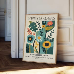 May include: A framed poster with a botanical illustration featuring stylized flowers and foliage in shades of teal, yellow, and red. The poster reads "KEW GARDENS" at the top, with additional text at the bottom indicating the nearest Underground station.