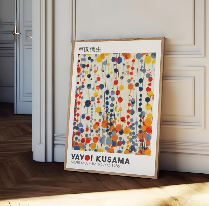 May include: A poster featuring a colorful abstract painting by Yayoi Kusama. The painting features a white background with a pattern of blue, red, yellow, and orange circles. The text "Yayoi Kusama" is printed in black at the bottom of the poster, along with the words "Mori Museum Tokyo 1985".