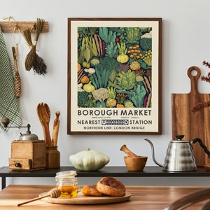 Puede incluir: Un p&oacute;ster enmarcado con un borde marr&oacute;n oscuro presenta una colorida ilustraci&oacute;n de varias verduras. El p&oacute;ster dice "BOROUGH MARKET" con el horario y la estaci&oacute;n de metro m&aacute;s cercana. El p&oacute;ster se muestra en un entorno de cocina con utensilios de madera y un molinillo de caf&eacute;.