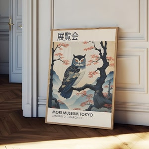 K&ouml;nnte beinhalten: Ein Plakat im Vintage-Stil, das eine Ausstellung im Mori Museum in Tokio bewirbt. Das Plakat zeigt eine blaue und wei&szlig;e Eule, die auf einem Ast eines Baumes mit rosa Bl&uuml;ten sitzt. Der Text auf dem Plakat lautet "展覧会" (Ausstellung) und "MORI MUSEUM TOKYO JANUARY 2 - MARCH 15".