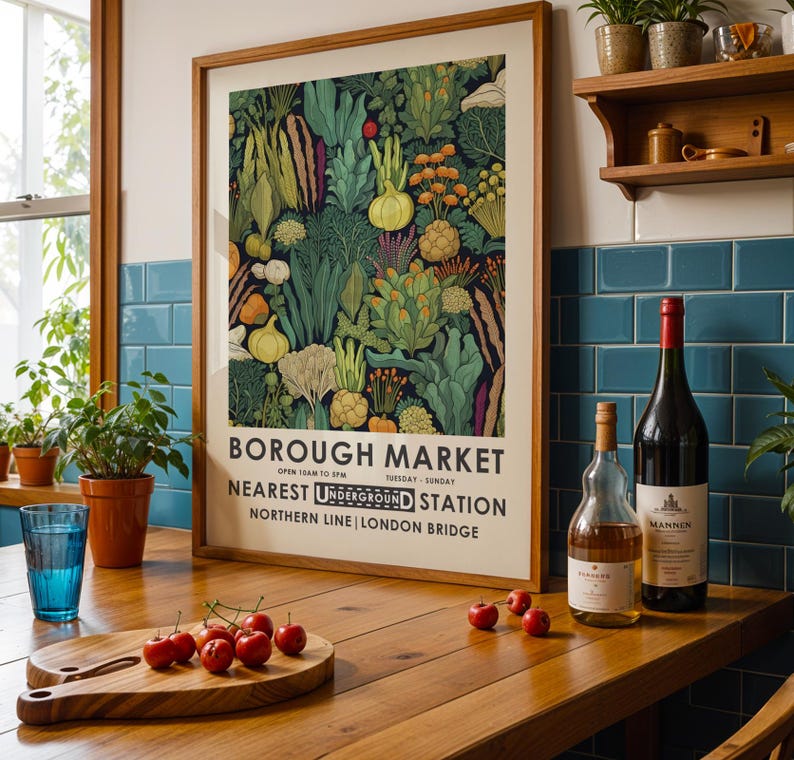 Puede incluir: Un p&oacute;ster enmarcado del mercado de Borough con una colorida ilustraci&oacute;n de verduras. Una tabla de cortar de madera con cerezas, un vaso de agua y botellas de vino est&aacute;n sobre una mesa de madera. Hay plantas en una estanter&iacute;a.