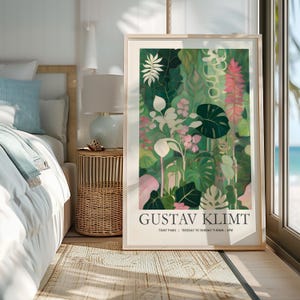 May include: A framed art print featuring a vibrant botanical illustration in shades of green, pink, and white. The artwork, signed "GUSTAV KLIMT," showcases lush foliage and flowers. The print is displayed in a light-colored frame, adding a touch of elegance to the room.