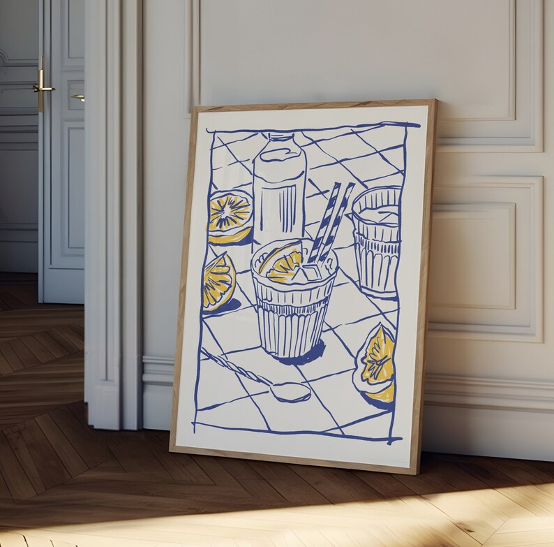 Pu&ograve; includere: Una stampa artistica incorniciata con un'illustrazione blu e gialla di una rinfrescante bevanda estiva. L'opera raffigura un bicchiere di limonata con ghiaccio, fette di limone, una bottiglia e un cucchiaio su una tovaglia a scacchi. La stampa &egrave; in una cornice di legno.