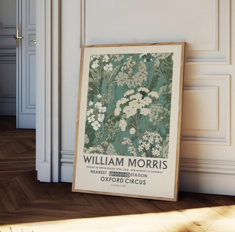 May include: A framed art print featuring a floral design in shades of teal, green, and white. The print includes the text "WILLIAM MORRIS" and other text about the history of British design and the Oxford Circus station.