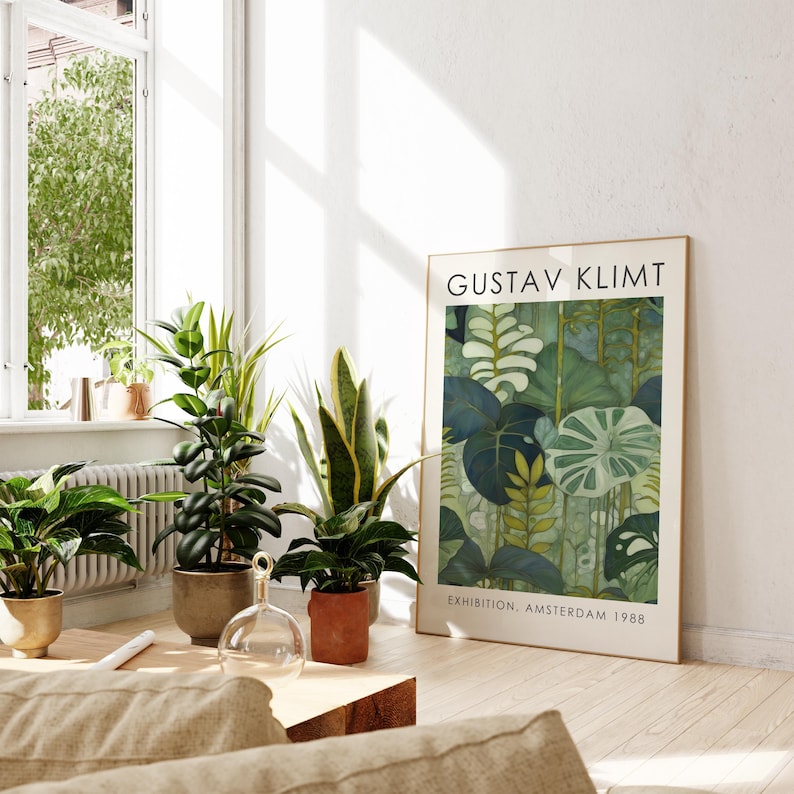 May include: A framed art print featuring a Gustav Klimt botanical illustration in shades of green and blue. The print is displayed in a bright room with several potted plants. Text on the print reads "GUSTAV KLIMT" and "EXHIBITION, AMSTERDAM 1988."