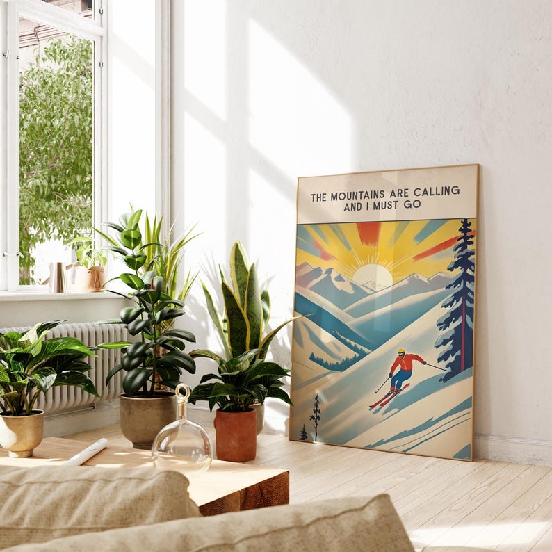 Op de afbeelding: Een vintage poster met een ski&euml;r op een berghelling. De poster heeft een geel, oranje en rood zonnestralenontwerp en de tekst "The Mountains Are Calling And I Must Go".