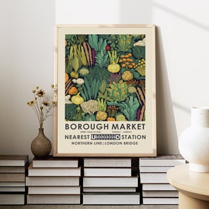 Puede incluir: Un p&oacute;ster enmarcado con una colorida ilustraci&oacute;n de verduras. El p&oacute;ster incluye el texto "BOROUGH MARKET" y detalles sobre la estaci&oacute;n de metro m&aacute;s cercana en Londres. La obra de arte se muestra sobre una pila de libros.