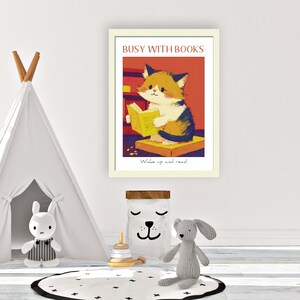 May include: A framed illustration of a cat reading a book. The illustration is in a cartoon style and features a cat with orange, white, and black fur. The cat is sitting on a yellow book and holding a book in its paws. The text on the frame reads "Busy with Books" and "Wake up and read".
