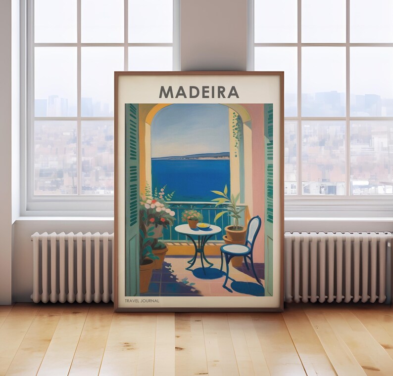 May include: A vintage travel poster with the word "MADEIRA" in bold, white letters on a pink background. The poster depicts a balcony overlooking a blue ocean with a table and chairs on the balcony. There are green plants and flowers on the balcony. The poster has the words "TRAVEL JOURNAL" at the bottom.