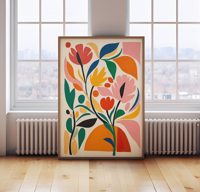 May include: A framed floral art print featuring a colorful abstract design. The artwork showcases stylized flowers and leaves in shades of red, pink, orange, yellow, green, and blue against a cream background. The print is displayed on a wooden floor near a window.