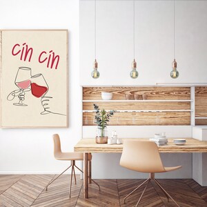 May include: A minimalist line art print of two wine glasses clinking with the text "cin cin" in red lettering on a beige background.