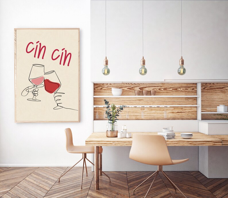 May include: A minimalist line art print of two wine glasses clinking with the text "cin cin" in red lettering on a beige background.
