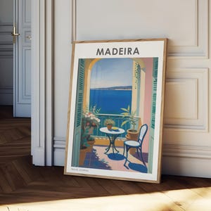 May include: A framed poster with a colorful illustration of a balcony overlooking the ocean. The poster has the word "MADEIRA" in white text at the top and "TRAVEL JOURNAL" in white text at the bottom.