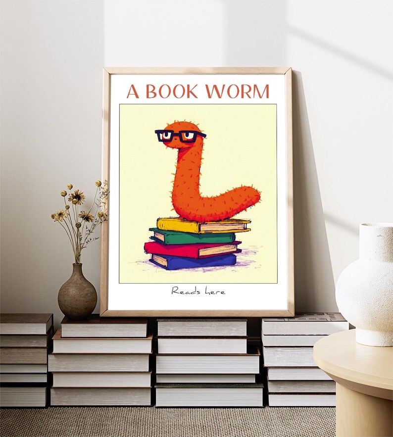 May include: A bookworm with glasses sits on top of a stack of colorful books. The text "A BOOK WORM" is at the top of the image and "Reads here" is at the bottom.