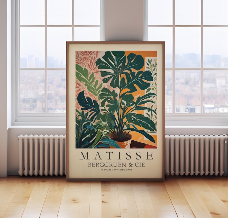Puede incluir: Un cuadro enmarcado con una ilustraci&oacute;n de una planta en maceta con grandes hojas verdes. La obra de arte, en tonos c&aacute;lidos, incluye el texto "MATISSE BERGGRUEN & CIE 70 RUE DE L'UNIVERSITE. PARIS". La impresi&oacute;n se muestra en una habitaci&oacute;n con una ventana.