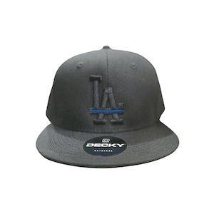 May include: A black baseball cap with a blue line and the letters "LA" embroidered on the front. The cap has a black "DECKY ORIGINAL" label on the underside of the brim.