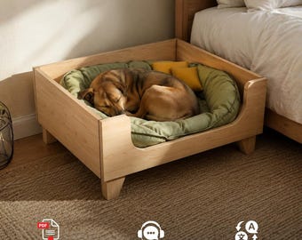 Puede incluir: Una estructura de cama para mascotas de madera clara con un diseño bajo y cuatro patas cortas. Dentro del marco hay una cama acolchada de color verde salvia con bordes elevados y dos pequeñas almohadas cuadradas de color amarillo mostaza, ocupada por un perro dormido.