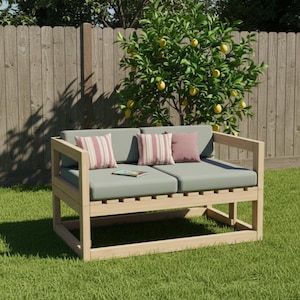 May include: A light-colored wooden outdoor loveseat with gray cushions and striped pillows. The loveseat is on a green lawn, with a wooden fence and a lemon tree in the background. A book rests on the cushions.