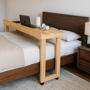 Könnte beinhalten: Ein helles Bett-Schreibtisch aus Holz mit einem Laptop, Kopfhörern und einem weißen zylindrischen Objekt. Der Schreibtisch hat eine rechteckige Tischplatte und wird von vier Beinen mit Rollen getragen. Der Bettrahmen ist dunkelbraun.