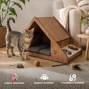 Può includere: Una cuccia per animali in legno marrone a forma di A con interno imbottito grigio scuro, dotata di un'apertura laterale con due ciotole in acciaio inossidabile. Un gatto tigrato si trova accanto, con un topolino giocattolo grigio e una palla.