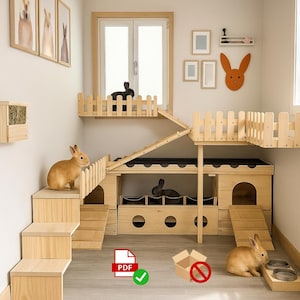 May include: A multi-level wooden rabbit hutch with stairs, ramps, and a fenced platform. The hutch has multiple compartments and a black roof. Two rabbits are visible inside the hutch. A wooden hay feeder is mounted on the wall.