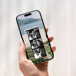 Op de afbeelding: Een smartphone toont een zwart-wit fotostrook van een stel. Het scherm van de telefoon toont een schilderachtig uitzicht op het meer. De telefoon wordt in een hand gehouden tegen een zachte, witte achtergrond.