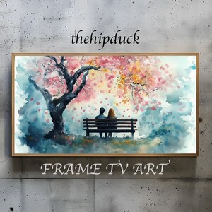 May include: Watercolor painting of a couple sitting on a bench under a cherry blossom tree. The artwork is framed in a gold-colored frame. The text "thehipduck" and "FRAME TV ART" are visible.