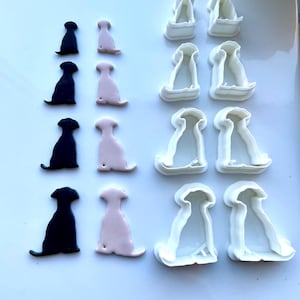 May include: A set of six dog-shaped cookie cutters. Three are white plastic, and three are black and pink plastic.