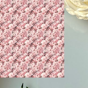 May include: A seamless pattern featuring pink cherry blossoms on a light pink background. The flowers are arranged in a repeating pattern, creating a delicate and feminine design.
