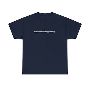 Puede incluir: Una camiseta azul marino con el texto "stop normalizing obesity." impreso en blanco en la parte delantera.