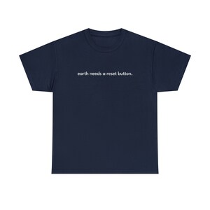 Puede incluir: Una camiseta azul marino con el texto "earth needs a reset button." impreso en blanco en la parte delantera.