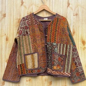 Puede incluir: Una chaqueta acolchada marrón con un diseño de patchwork. La chaqueta tiene un cierre de botón y dos bolsillos.