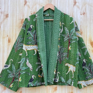 Könnte beinhalten: Eine grüne gesteppte Jacke mit Blumen- und Tierdruck. Die Jacke hat ein Muster aus Tukanen, Leoparden und Palmen.
